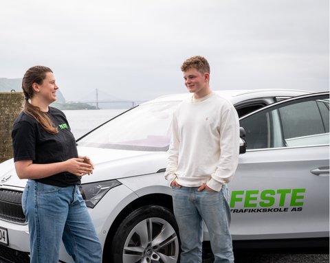 Feste trafikklærer med elev utenfor bil